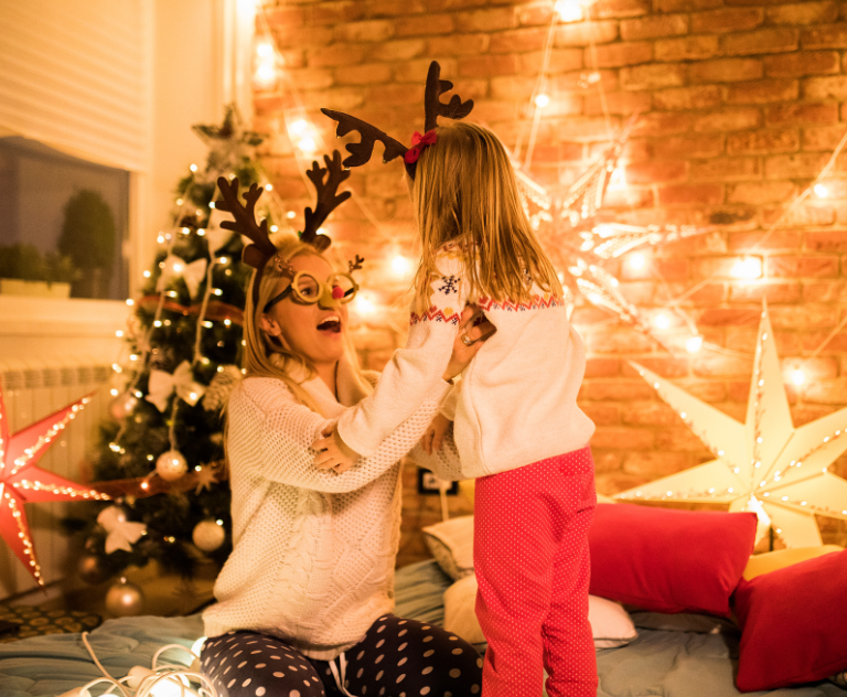 parent and child enjoying  cosy, budget-friendly Christmas festivities at home with festive lights and decorations.
