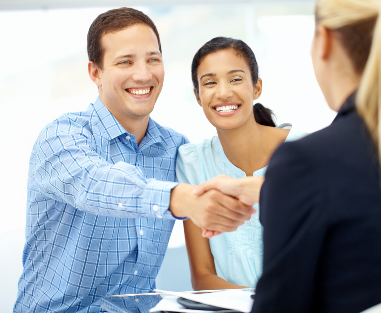 Happy couple shaking hands with the loans officer after completing application process.